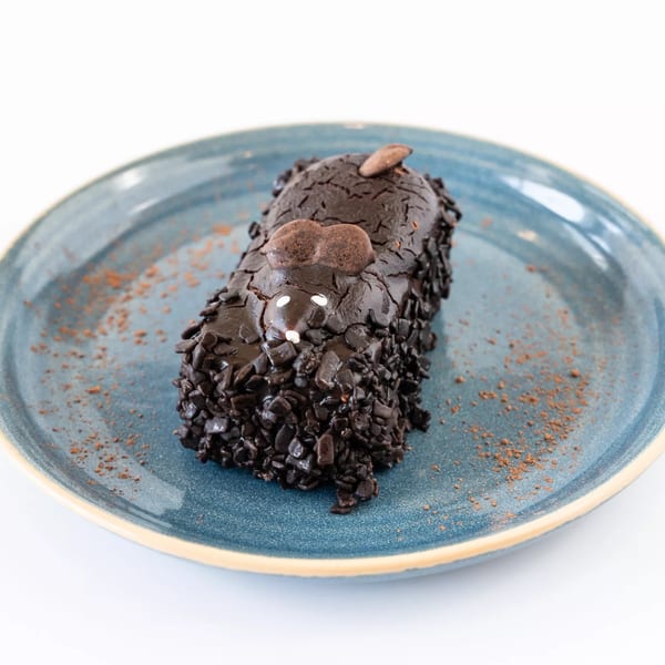 Chocolate cake shaped like a mouse, covered in chocolate sprinkles, on a blue plate.