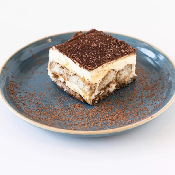 A slice of tiramisu with cocoa powder on a blue plate at Anthony's Restaurant.