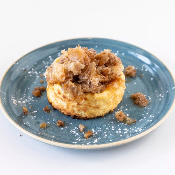 A cheesecake topped with caramelized onions and powdered sugar on a blue plate.